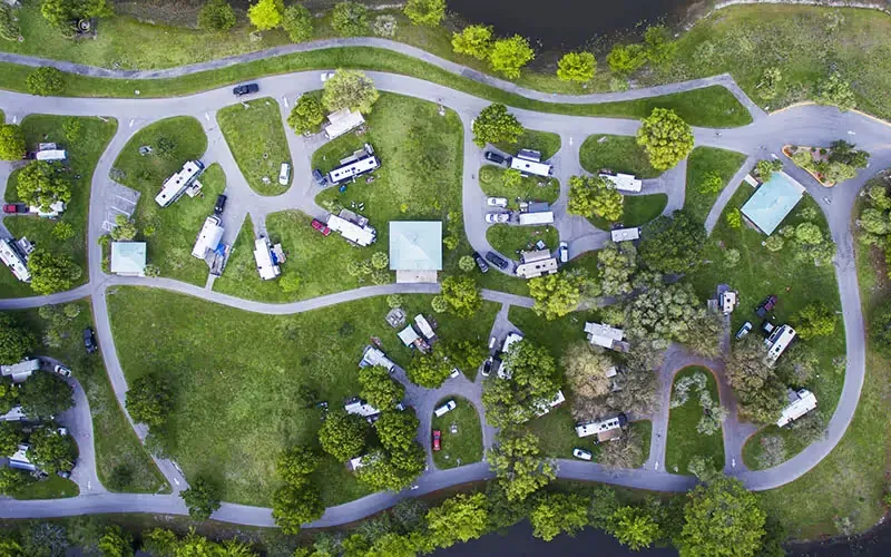 A park with a lake and a bunch of trailers.